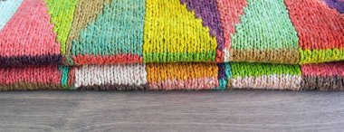Ahşap arka plan üzerinde renkli beyaz, sarı, kahverengi, pembe, yeşil, mavi, Turkuaz, turuncu, Bordo el yapımı örgü yün hırka. Rustik yün. Afiş