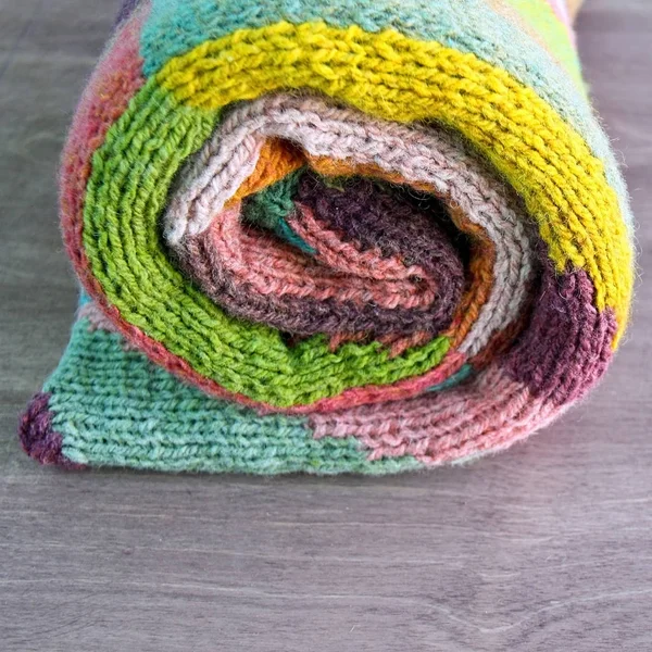 Coloré blanc, jaune, brun, rose, vert, bleu, turquoise, orange, claret cardigan en laine tricotée à la main sur le fond en bois. De la laine rustique. Comme l'escargot — Photo