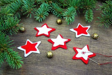 Noel partisi hazırlık arka plan kırmızı anf beyaz iplik, iğneyi hissettim, dikiş yıldız rakamları ile Noel ağacı doğal taze dalları yakınındaki altın çan kahverengi doğal ahşap zemin üzerinde çeki düzen vermek. El yapımı yılbaşı süsleme. Portre. 