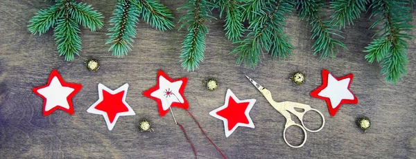 Anf 縫製星のクリスマス パーティー準備の背景は 針と糸 はさみ 茶色の自然な木製の背景にトウヒのクリスマス ツリーの新鮮な自然の枝の近くの金の鈴を感じた 作られたクリスマスの飾りを手 — ストック写真