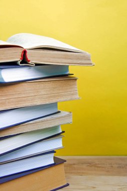 Geri okul ve bilgi kavramı. Ahşap arka plan ve sarı duvar üzerinde kitap yığını. Önden görünüm