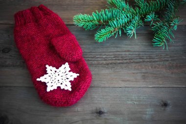 Rustik ahşap zemin üzerine yeşil Noel kürk tree yakınındaki Pamuk Tığ işi kar tanesi ile kırmızı yün mitten ile. Tonda. Noel kartı, kartpostal kavramı. Önden görünüm