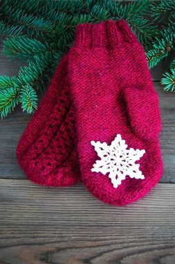 Rustik ahşap zemin üzerine yeşil Noel kürk tree yakınındaki Pamuk Tığ işi kar tanesi ile kırmızı yün eldiven ile. Tonda. Noel kartı, kartpostal kavramı. Önden görünüm