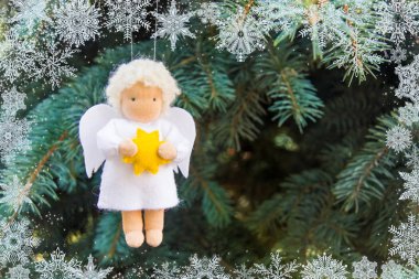 Beyaz kar taneleri ile fir Noel ağacı üzerinde Noel meleği sarı yıldız ile eller hissettim. Kış kart kavramı