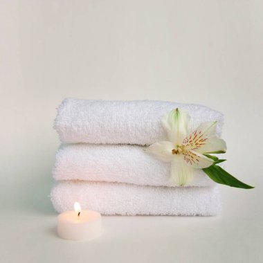 Güzel alstroemeria çiçek, yanan mum ve üç temiz beyaz spa salon banyo havlusu beyaz arka plan üzerinde izole yığını. Önden görünüm kopya alanı yakın çekim
