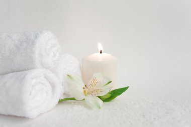 Güzel alstroemeria çiçek, yanan mum ve üç beyaz arka plan üzerinde izole temiz beyaz spa salon banyo havlusu rulo. Önden görünüm kopya alanı yakın çekim