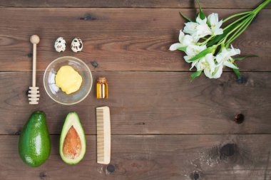 Malzemeler vitamini Avokado cilt bakımı cilt bakımı için maske yeşil limon, şişe Kozmetik yağı, bal, kepçe, yulaf gevreği, kahverengi ahşap zemin üzerinde saç fırçası. Alstroemeria çiçek. Üstten görünüm Kopyala yer kapatın