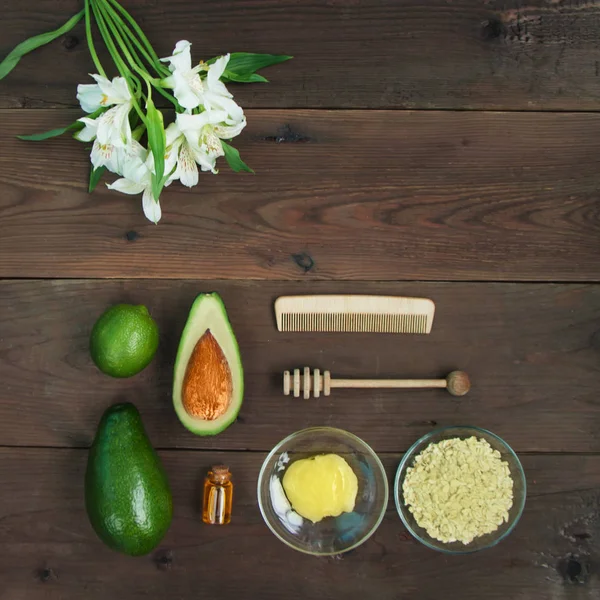 Malzemeler vitamini Avokado cilt bakımı cilt bakımı için maske yeşil limon, şişe Kozmetik yağı, bal, kepçe, yulaf gevreği, kahverengi ahşap zemin üzerinde saç fırçası. Alstroemeria çiçek. Üstten görünüm Kopyala yer kapatın
