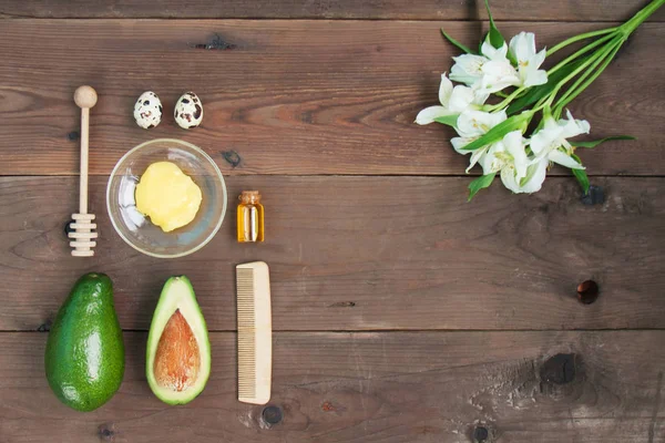 Malzemeler vitamini Avokado cilt bakımı cilt bakımı için maske yeşil limon, şişe Kozmetik yağı, bal, kepçe, yulaf gevreği, kahverengi ahşap zemin üzerinde saç fırçası. Alstroemeria çiçek. Üstten görünüm Kopyala yer kapatın