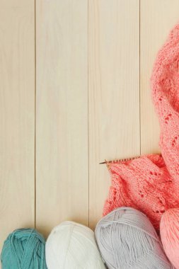 Örgü işlemi yün gri ahşap örgü iğne üzerinde yapılan bir mercan Cardigan, turkuaz mavi, beyaz iplik topları ve metal makas ahşap Komiteler arka plan üzerinde. Kopyalama alanı en iyi görünüm düz yatıyordu