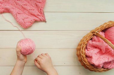 Bir mercan yün iplik bir karigan ile ahşap örgü iğneleri bir ajur düzeni ve parlak ahşap rustik arka plan üzerinde bir sepet örgü sürecinde bir topa elle. Düz yatıyordu üstten görünüm