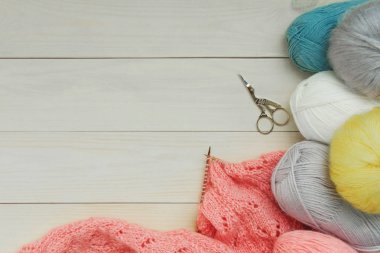 Mercan hırka yün gri, turkuaz mavi, sarı beyaz iplik topları, arka plan parlak ahşap kurulların metal makaslar ahşap örgü iğne üzerinde yapılan işlem. Kopyalama alanı en iyi görünüm düz yatıyordu