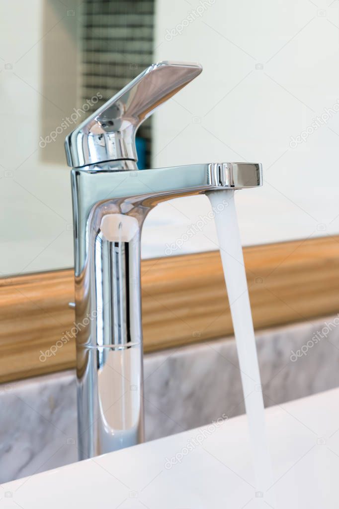 Modern style tap at sink in bathroom pouring water