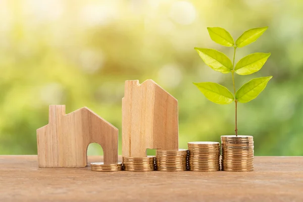 Model house and coin stack with plant on green tree background mortgage saving concept