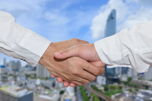 Business people shake hand in front of financial district
