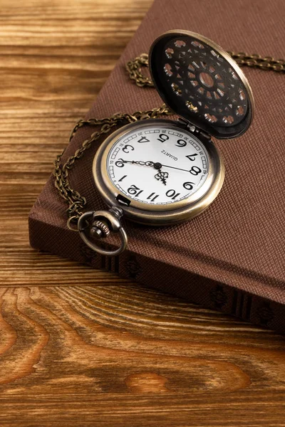 Vintage zakhorloge klok met boek op houten achtergrond — Stockfoto