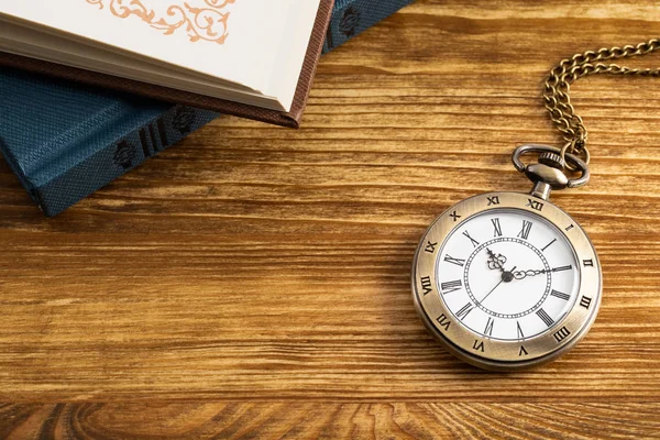 Vintage zakhorloge klok met boek op houten achtergrond — Stockfoto