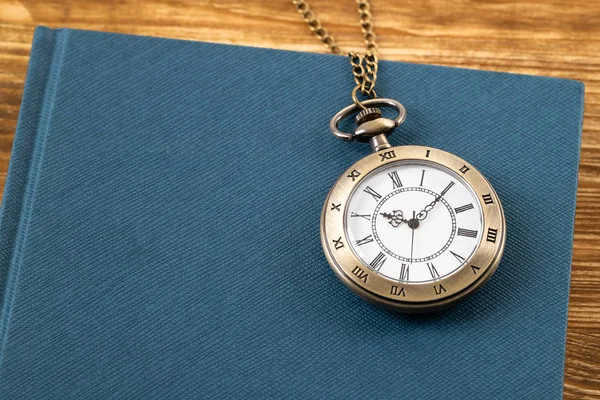 Vintage zakhorloge klok met boek op houten achtergrond — Stockfoto