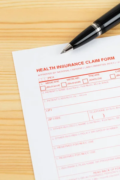 Formulário de pedido de seguro de saúde com caneta na mesa de madeira — Fotografia de Stock