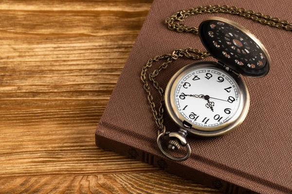 Reloj de bolsillo vintage con libro sobre fondo de madera — Foto de Stock