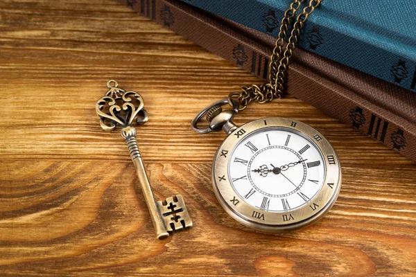 Vintage zegarek kieszonkowy z kluczem i książki na drewnianym tle — Zdjęcie stockowe