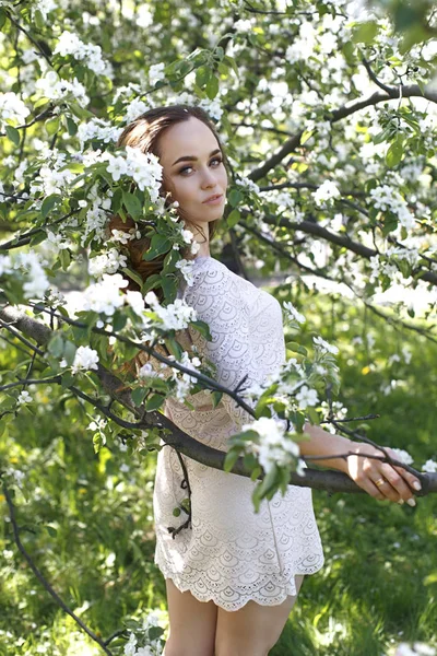 女孩在黄色春天礼服反对绽放苹果树的背景 免版税图库图片