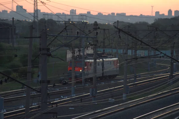 Train in motion on rails, evening urban landscape.