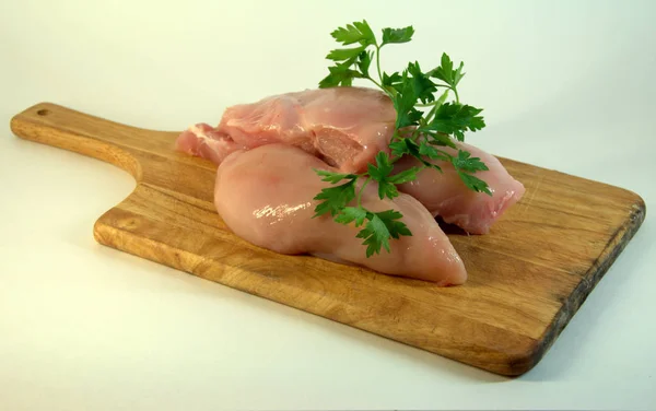Chicken white meat, fillets, on a chopping board with parsley. A picture on a white background close-up.
