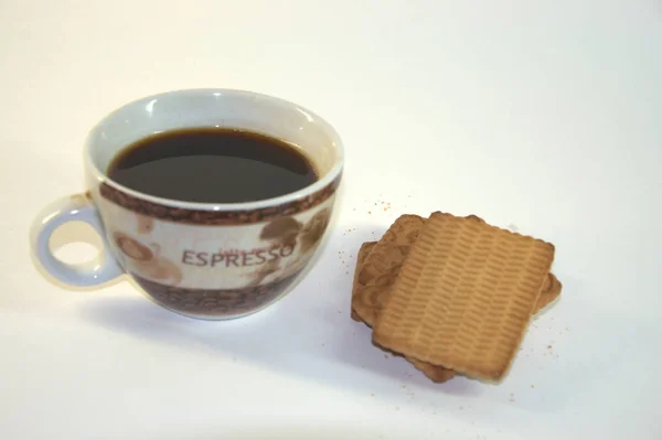 A cup of black coffee and a few slices of shortbread. A close-up shot on a white background.