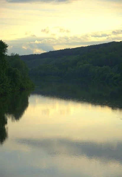 Calm flow of the river at the side of a hill, shot at sunset. landscape.