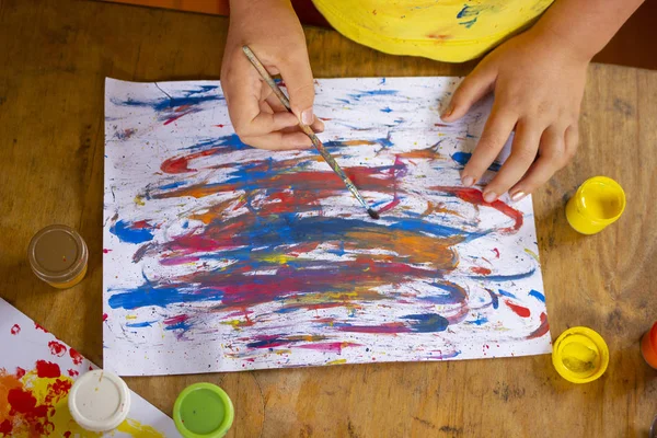 Fırça çizen çocuk eli. Çocuk üst görünümü çiziyor. Suluboya ve guaj kullanarak resim yapan güzel bir kız.