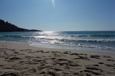 Altın plajda gün doğumu Thassos Yunanistan, yükselen güneşin gümüş parıltısı gök mavisi denizin dalgaları üzerinde