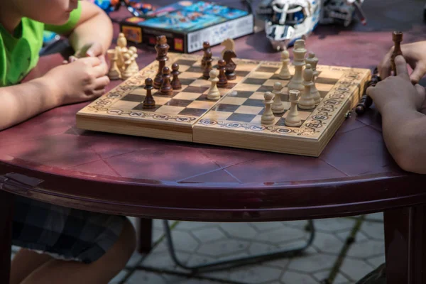 kids playing chess in garden with blurred toys on background