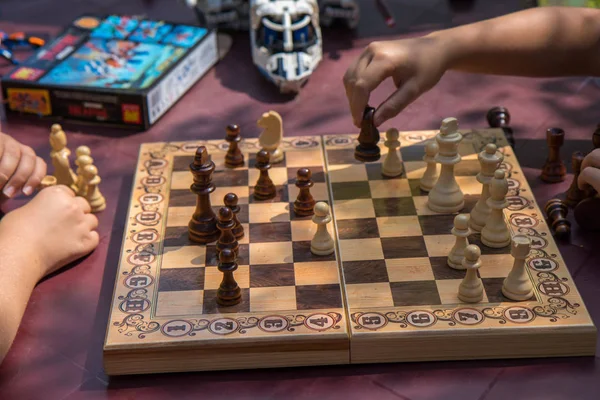 Kids playing chess in garden with blurred toys on background — Stock Photo, Image