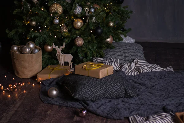 Décor d'hiver : sapin de Noël, guirlande, boules, cadeaux et tresses douillettes rayées et grises avec oreillers — Photo