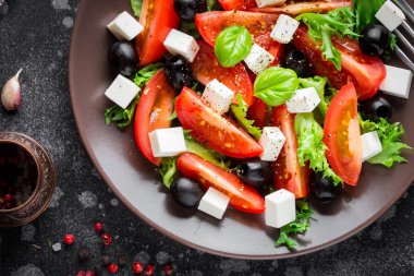 Salata Domates, beyaz peynir, zeytin ve fesleğen, tatsy gıda, karanlık bir arka plan hizmet ile