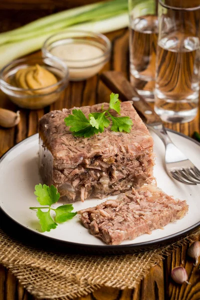 Jelly with meat, beef aspic, traditional Russian dish, portion on a plate, mustard and horseradish