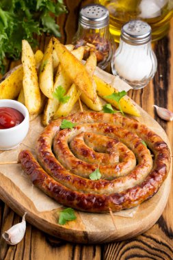 Bitki patates ve ketçap, lezzetli Yaz piknik tabak, sosis şiş üzerinde ızgara sosis bükülmüş karanlık bir ahşap zemin üzerine bir daire içinde