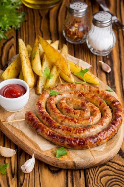 Bitki patates ve ketçap, lezzetli Yaz piknik tabak, sosis şiş üzerinde ızgara sosis bükülmüş karanlık bir ahşap zemin üzerine bir daire içinde