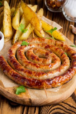 Bitki patates ve ketçap, lezzetli Yaz piknik tabak, sosis şiş üzerinde ızgara sosis bükülmüş karanlık bir ahşap zemin üzerine bir daire içinde