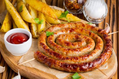 Bitki patates ve ketçap, lezzetli Yaz piknik tabak, sosis şiş üzerinde ızgara sosis bükülmüş karanlık bir ahşap zemin üzerine bir daire içinde