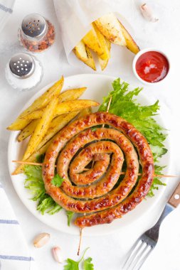 Bitki patates ve ketçap, lezzetli Yaz piknik tabak, sosis şiş üzerinde ızgara sosis bükülmüş hafif bir arka plan üzerinde bir daire içinde