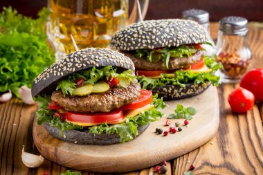 Burger siyah topuz, Dana pirzola, domates, peynir, salata, bira, lezzetli ev yapımı sandviç ile hızlı gıda