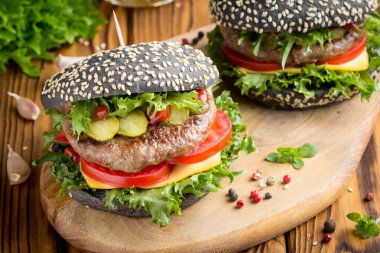 Burger siyah topuz, Dana pirzola, domates, peynir, salata, bira, lezzetli ev yapımı sandviç ile hızlı gıda