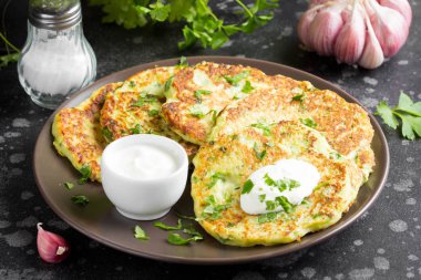 Kabak gözlemesi maydanoz, sarımsak ve ekşi krema, yaz yemek, lezzetli Aperatif. Karanlık bir arka plan üzerinde koyu bir tabak içinde