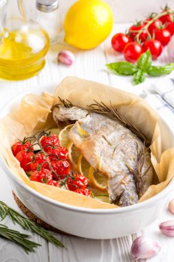 Kabak, domates şube, biberiye ve limon ile seramik pişirme çanağı içinde pişmiş beyaz alabalık balık. Sağlıklı diyet gıda