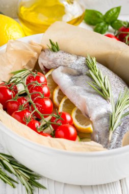 Akşam yemeği, kabak, domates bir şube, biberiye ve limon ile bir pişirme çanağı çiğ beyaz alabalık balık. Sağlıklı diyet gıda