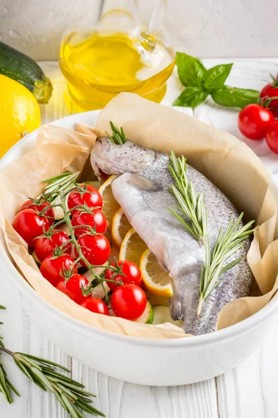 Akşam yemeği, kabak, domates bir şube, biberiye ve limon ile bir pişirme çanağı çiğ beyaz alabalık balık. Sağlıklı diyet gıda