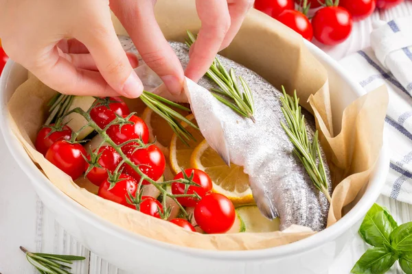 Akşam yemeği, kabak, domates bir şube, biberiye ve limon ile bir pişirme çanağı çiğ beyaz alabalık balık. Sağlıklı diyet gıda