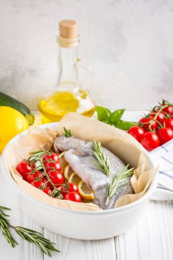 Akşam yemeği, kabak, domates bir şube, biberiye ve limon ile bir pişirme çanağı çiğ beyaz alabalık balık. Sağlıklı diyet gıda